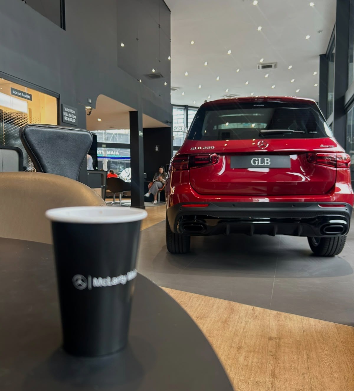 Interior de concessionária com um Mercedes-Benz GLB vermelho ao fundo
